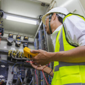 Técnico con equipo de protección inspeccionando panel eléctrico como parte de entrenamiento en prevención de riesgos eléctricos.